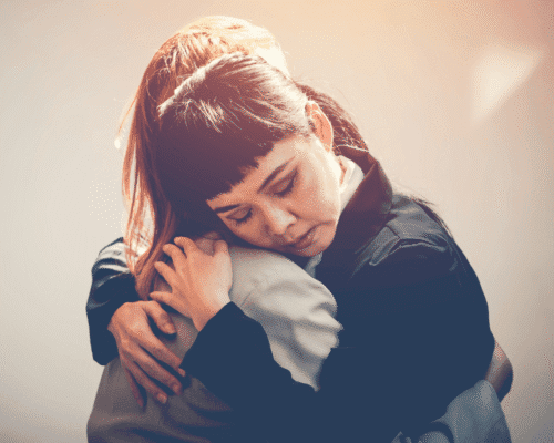 Grieving woman embracing another