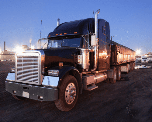 Black tractor-trailer truck parked at dusk with headlights reflecting off its chrome grille, symbolizing Georgia truck crash legal tips. The image highlights tractor-trailer accident mistakes, evidence preservation, trucking company insurance, and early settlement offers in truck accident claims.