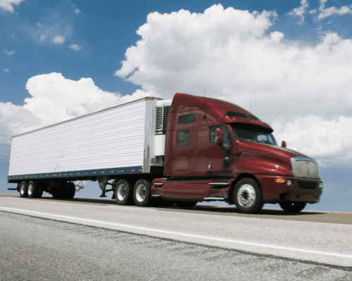 Red semi-truck drives down the highway under a blue sky with clouds, symbolizing Georgia State Patrol crash report Columbus. The image highlights accident reconstruction, police report evidence, truck accident GSP form, and car crash documentation used in personal injury claims.