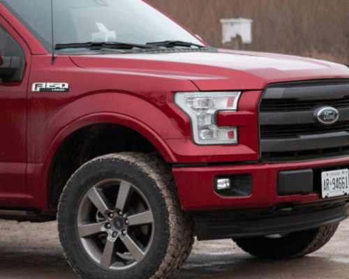 Red pickup truck parked on a dirt surface, highlighting vehicle structure relevant to roof crush resistance and federal safety standards in rollover and product liability cases.