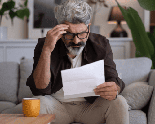 Man reviewing a denied insurance claim letter at home, illustrating stress and legal options after a motorcycle accident claim denial in Columbus, Georgia.