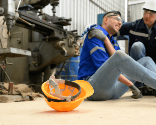 A construction site accident scene where an injured worker sits on the ground in visible pain while a coworker assists, highlighting the serious risks construction workers face and the potential legal rights available—even for undocumented workers injured on the job in Atlanta.