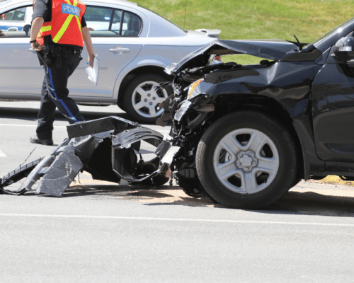 Damaged vehicle after a crash in Columbus, Georgia, with police investigating the scene, illustrating potential claims involving defective vehicle parts and manufacturer liability under Georgia law.