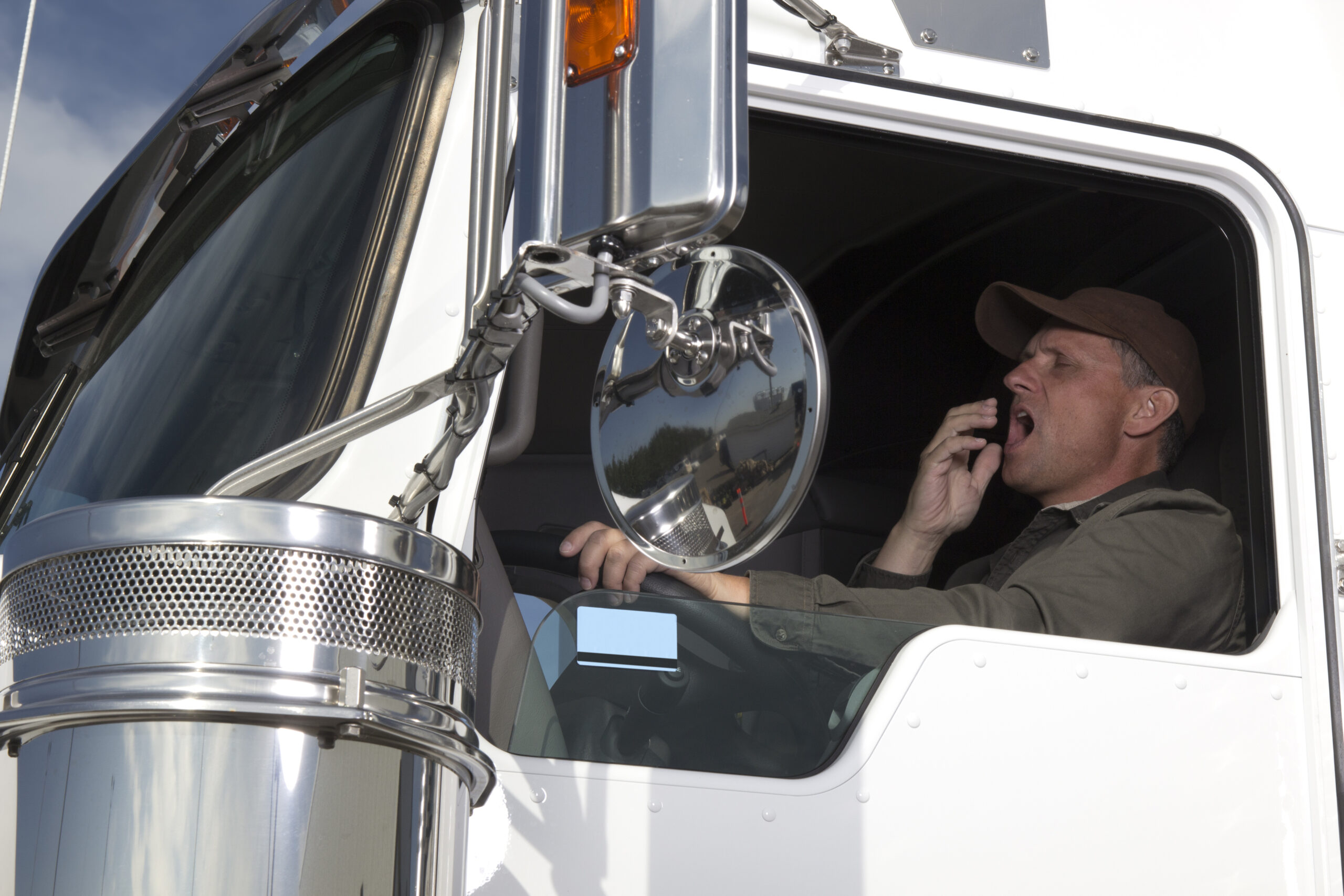 A truck driver yawns while driving.