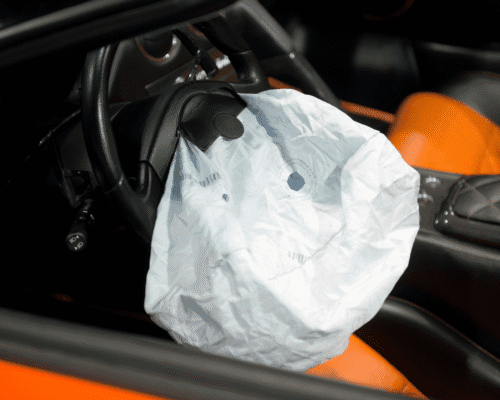 Deployed airbag inside a car with orange interior, symbolizing how to file a lawsuit for defective airbags in Georgia. The image highlights tractor-trailer accident mistakes, evidence preservation, trucking company insurance, and early settlement offers in defective airbag injury cases.