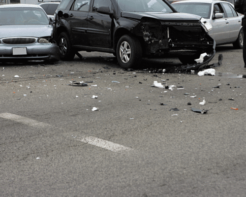 Three damaged vehicles at an intersection after a collision, with debris scattered across the road and a police officer inspecting the scene, illustrating a multi-vehicle truck accident in Columbus, Georgia and the complexities of determining fault and liability in chain-reaction crashes involving tractor-trailers.