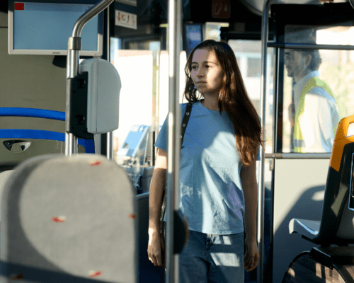 Passenger standing inside a city bus near the fare area while the driver is visible in the background, representing public transit conditions involved in a bus accident investigation.